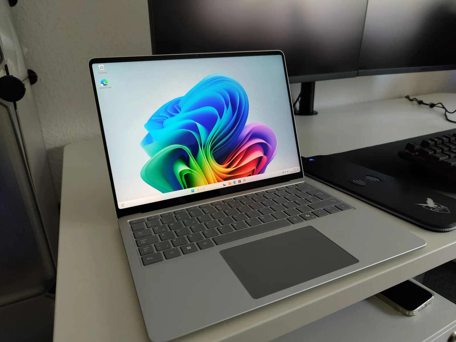 Surface Laptop aufgeklappt auf dem Schreibtisch vor zwei Monitoren